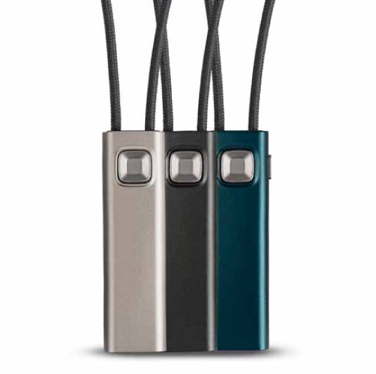 Three rectangular Widex COM-DEX devices in silver, black, and teal, each with a square button and looped black cord at the top, are displayed side by side on a white background.